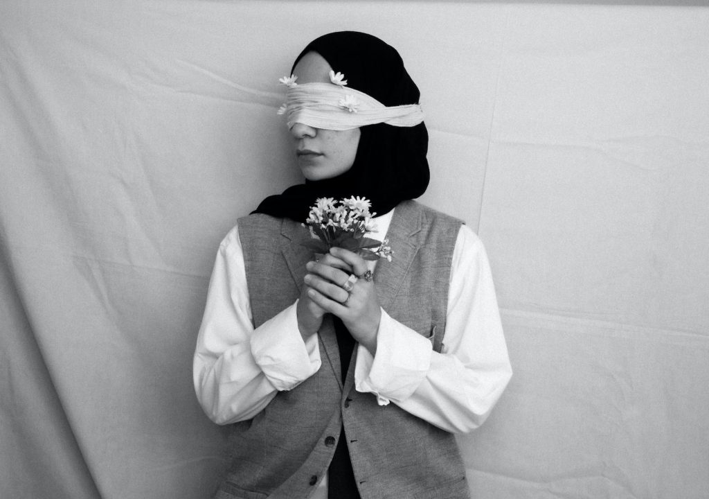 black and white picture of a blindfolded woman holding bunch of flowers