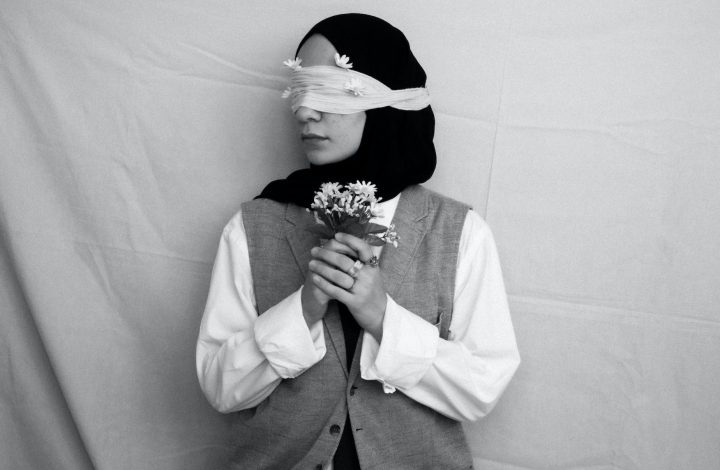 black and white picture of a blindfolded woman holding bunch of flowers