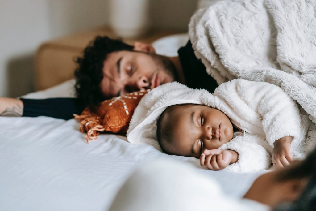 unrecognizable ethnic mother relaxing near baby sleeping with father on bed
