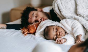 unrecognizable ethnic mother relaxing near baby sleeping with father on bed