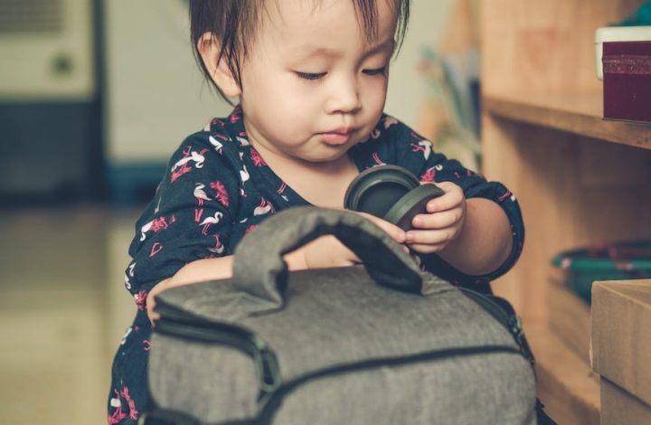 baby girl playing with a camera bag on an apartment floor