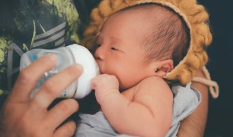 a newborn baby drinking milk from feeding bottle