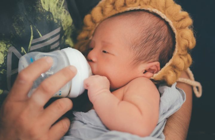 a newborn baby drinking milk from feeding bottle